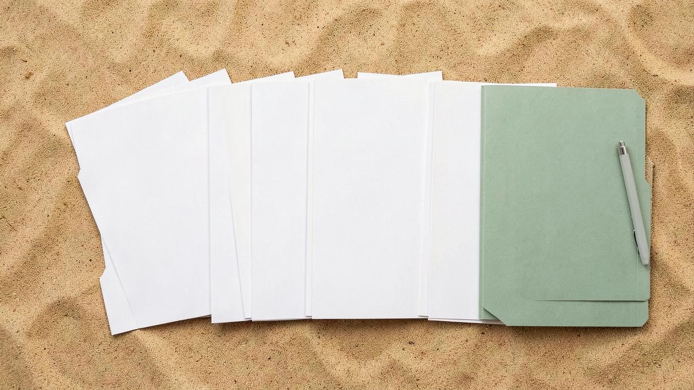 Blank paper folders fanned out in a row on a warm sand desk with a sage green folder and pen